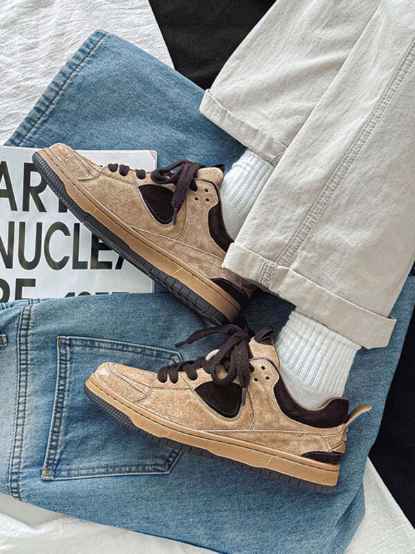 A person wearing beige and black sneakers paired with white ribbed socks and light beige pants, with the feet resting on a blue denim jacket and a magazine.